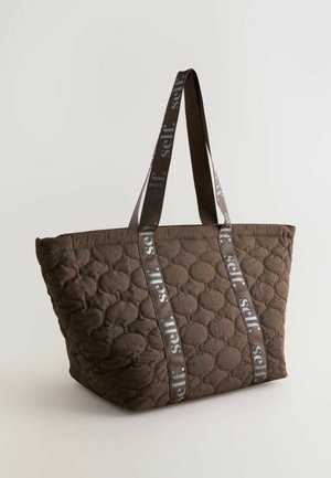 Brun quiltet taske med afrundede, quiltede mønstre og dobbelt stofhåndtag med gentagende "self." tekst i grå.