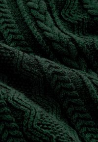 Tejido de punto verde con patrones de cable elevados, textura suave y apariencia gruesa y abrigadora. Vista de cerca que resalta el diseño detallado.