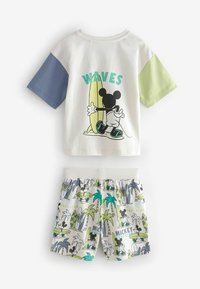 T-shirt bianca a maniche corte con maniche blu e verdi, che presenta una grafica di Topolino. Pantaloni corti coordinati con motivi di palme e tavole da surf.