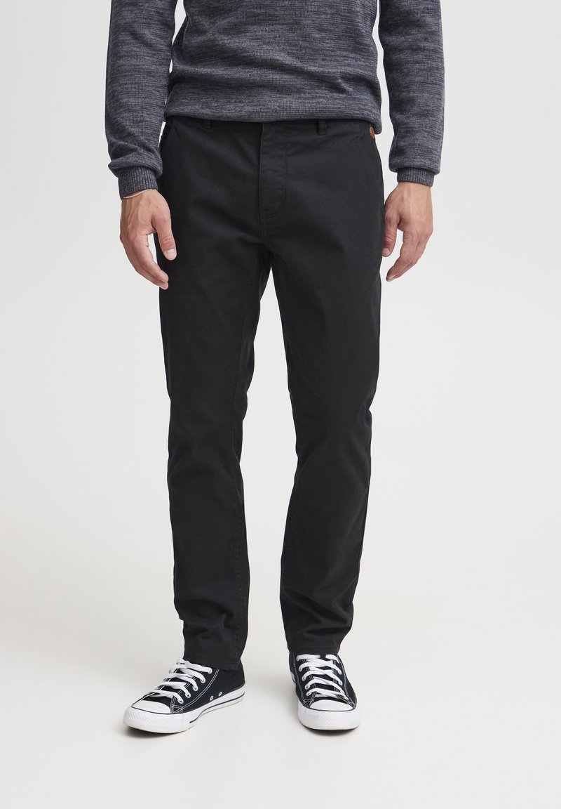 Sorte bomullsbukser med rett benpassform, med frontlommer og et minimalt design. Kombinert med sorte kanvas sneakers.