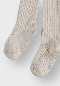 Chaussettes côtelées beige clair en matériau texturé avec un léger éclat. Présentent des orteils renforcés et un ajustement confortable pour un port quotidien.