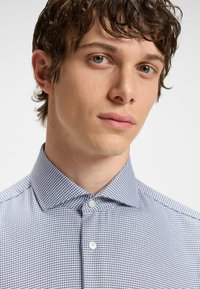 Camicia button-up a maniche lunghe blu e bianca con colletto alla francese e tessuto liscio. Presenta piccoli quadrati in un design a griglia.