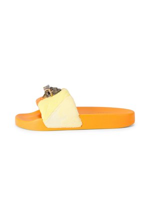 Oranje slippers met gele stoffen band voorzien van een metalen uilenversiering op een witte achtergrond.