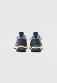 Des chaussures de sport avec un design bleu et noir, un matériau texturé, des languettes de traction et des accents colorés sur la semelle.