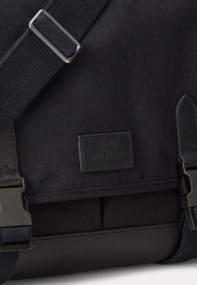 Borsa a tracolla nera in tela con una morbida toppa in pelle, ganci metallici e tessuto testurizzato con una forma strutturata.