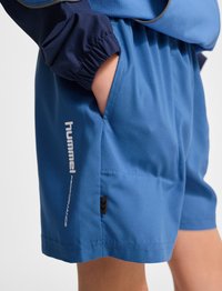 Blå sportshorts gjorda av lättviktigt material, med elastisk midja, sidofickor och en tryckt logotyp på benet.