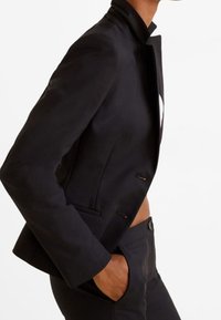 Černý blejzr z strukturovaného materiálu, s klopovým límcem, dvěma předními kapsami a slim fit střihem. Design má čistou, minimalistickou siluetu.