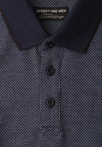 Polo homme bleu marine avec motif en maille texturée, trois boutons noirs et un large col côtelé avec bordure foncée.