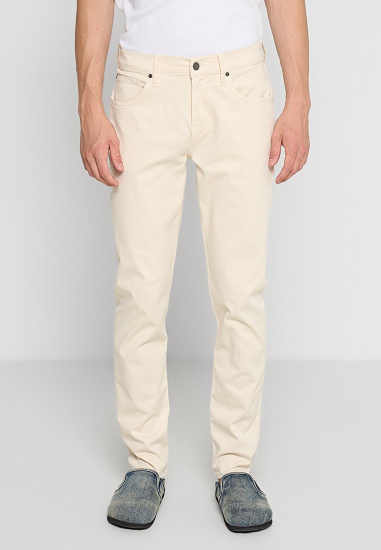 Beige katoenen chinos met een slim fit, vijf zakken en een knoopsluiting bij de taille. De stof heeft een gladde textuur.