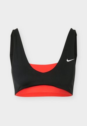 Sujetador deportivo Nike en negro y rojo con tirantes anchos y escote redondeado, con un logo Nike en forma de swoosh blanco en el lado izquierdo.