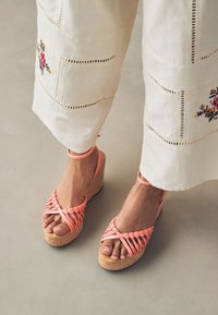 Pink vævede kilehøjhælede sandaler med korkhæle og ankelstropper, med et kryds-design og åben tå-stil.