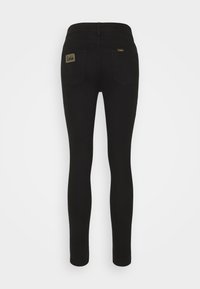 Vaqueros negros ajustados con una textura suave, cintura alta y parche con logo en el bolsillo trasero. Cuenta con dos bolsillos traseros y un diseño de ajuste slim.