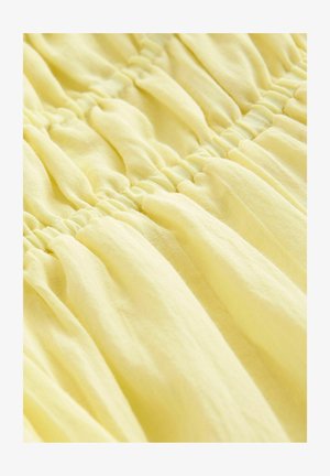 Jasnożółta tkanina o marszczonym wyglądzie, z elastycznymi detalami, które nadają jej miękki, luźny wygląd.
