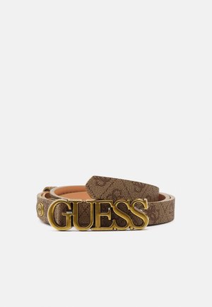 Bruine leren riem met patroon en grote gouden gesp waar de merknaam GUESS op staat, opgerold op een witte achtergrond.