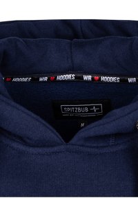 Felpa blu navy con una texture morbida, dotata di un'etichetta nera "SPITZBUB" e di una fascia interna decorata con la scritta "WIR ♥ HOODIES." Taglia M.