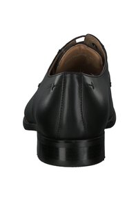 Chaussures en cuir noir avec une texture lisse, un bout arrondi et un petit talon empilé. Elles présentent des détails de couture et un design à talon ouvert.