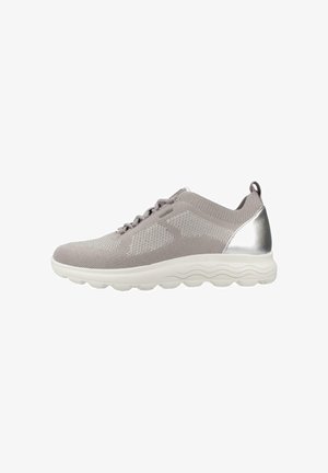 Zapatillas deportivas de color gris claro con una parte superior de malla transpirable, acento plateado en el talón y una suela blanca texturizada con patrones en forma de ola.