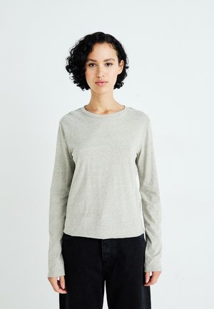 Grijze lange mouwen shirt van zachte stof, met een ronde halslijn en een relaxte pasvorm, gecombineerd met donkere broeken.