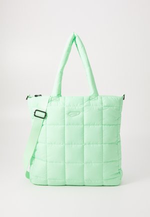Light green quilted tote bag with padded texture, short handles, adjustable shoulder strap, and a zippered closure. Features a logo detail.