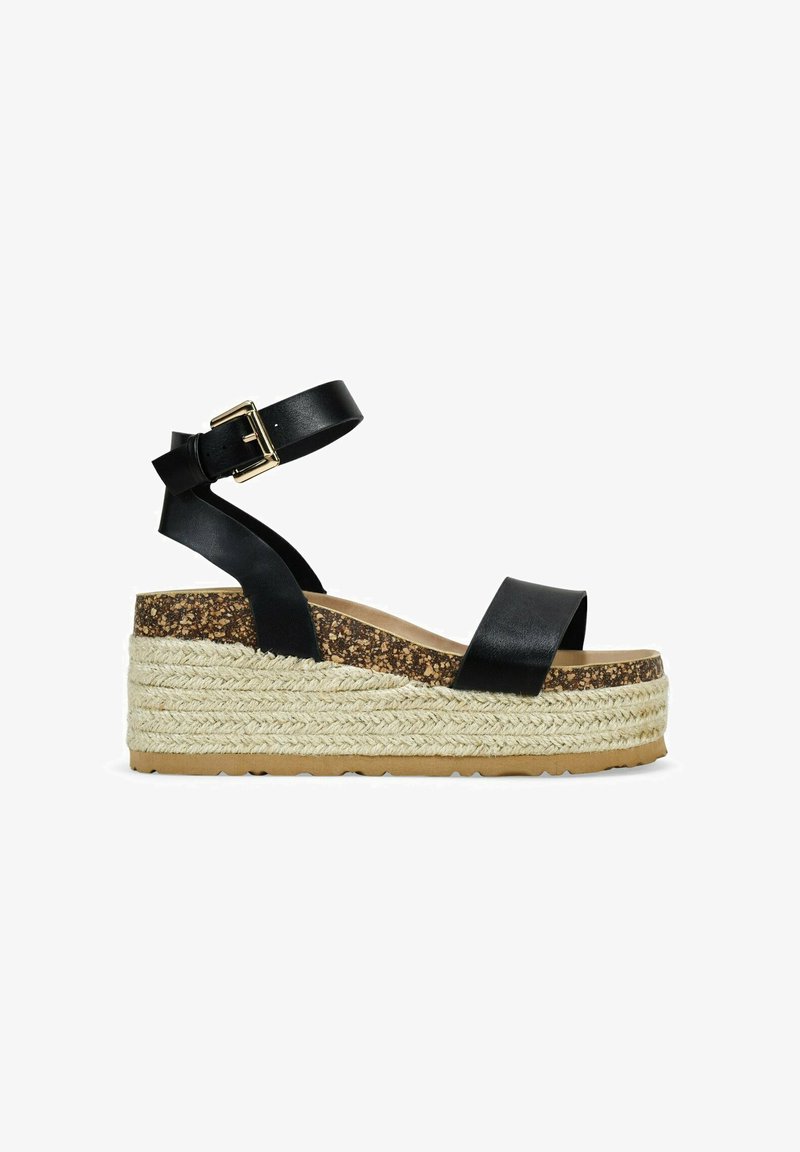 Sandalia de cuña de cuero negro con tira en el tobillo, plantilla de corcho y plataforma envuelta en yute. Cuenta con una hebilla para un ajuste ajustable.