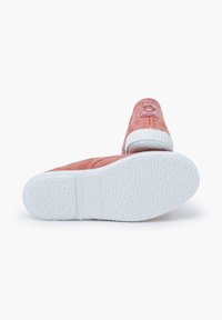 Scarpe di tela rosa con suole in gomma bianca, suola testurizzata e un'etichetta cucita che presenta una scimmia sul tallone.