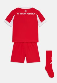 Kit sportivo giovanile del FC Bayern München, composto da una maglietta rossa con colletto e maniche bianche, pantaloni corti rossi e calzini rossi abbinati con logo.