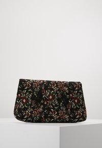 Bolso de mano de tela negra con estampado floral, con detalles en rojo y verde. Forma rectangular estructurada con superficie texturizada.