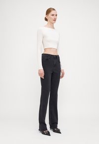 Black straight-leg jeans with front pockets and belt loops, paired with a fitted white long-sleeve crop top. Footwear features pointed toes.