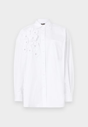 Biela dlhá košeľa s dlhým rukávom a gombíkovým zapínaním, na ľavej strane s aplikáciami kvetov a náprsné vrecko. Mäkká, hladká látka.