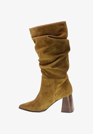 Bottes en daim marron, montantes, avec un design ample, bout pointu et un talon épais de couleur bois. Texture lisse et finition douce.