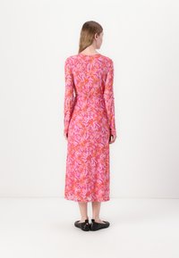 Rochie maxi cu mânecă lungă, de culoare roz, cu modele florale portocalii, confecționată dintr-un material ușor, având un cordon la talie și o croială lejeră. Se poartă cu balerini negri.