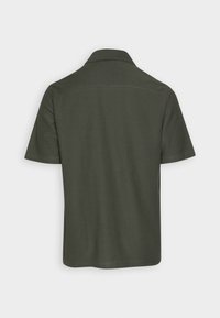 Polo shirt verde scuro a maniche corte con colletto, mostrato da dietro su uno sfondo chiaro e semplice.