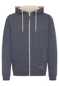 Sweat à capuche bleu marine zippé avec cordons beiges, capuche attachée, poche kangourou avant, poignets et ourlet côtelés.