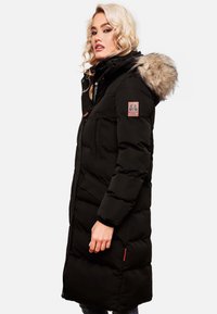 Black padded winter coat with a fur-lined hood, zippered and pocket details, featuring a pink logo patch and orange accents.