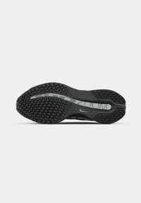 Semelle en caoutchouc noir d'une chaussure de course avec une adhérence texturée et un logo blanc Nike Zoom visible au niveau du médio-pied.