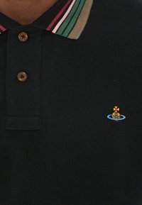 Fekete póló, három gombos gallérral, zöld, rózsaszín és barna csíkos gallérral, kicsi hímezett csónak mintával a mellrészen.