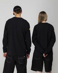 Cămăși negre cu mânecă lungă și guler rotund, purtate cu pantaloni scurți negri. Accente brodate în galben pe mâneci. Design simplu, lejer.