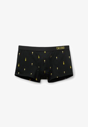 Boxer ajustados negros de algodón, con un patrón repetido de botellas y copas de champán en amarillo. Cintura elástica con el texto "¡SALUD!".