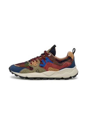 Sneaker multicolore con inserti in camoscio e tessuto, lacci blu, suola bianca spessa e battistrada nero, mostrata dal lato esterno su sfondo bianco.