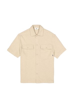 Chemise beige à manches courtes en tissu texturé, avec un col à revers, deux poches poitrine et une fermeture boutonnée sur le devant.
