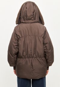 Bruine opblaasbare jas met elastische tailleband en grote capuchon voorzien van een textuur fleece voering. Lange mouwen met manchetten en een gestroomlijnd ontwerp.