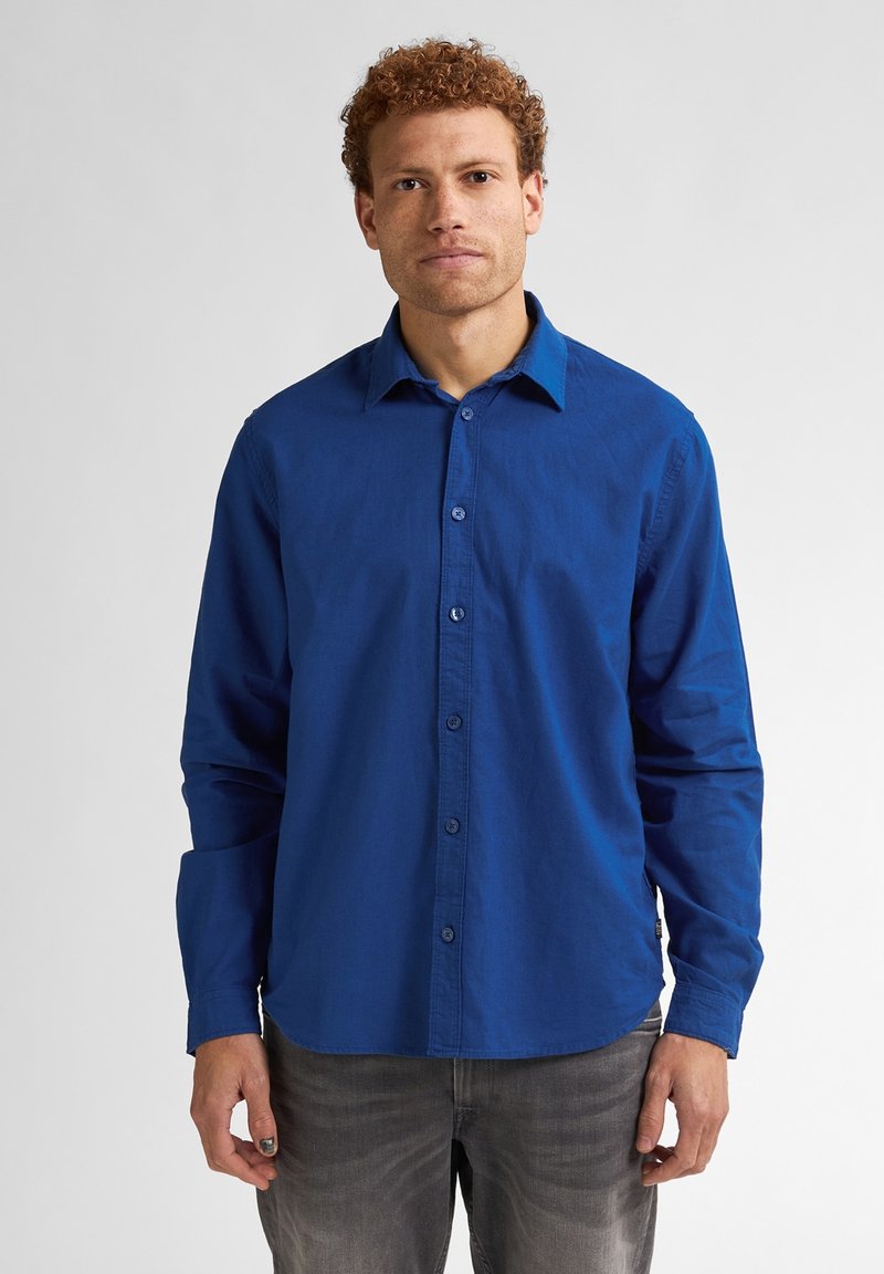 Modrá košile na knoflíky vyrobená z hladké tkaniny, s límečkem, dlouhými rukávy a přímým lemem, doplněná o ladící knoflíky.
