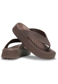 Bruine rubberen teenslippers met een dikke zool, geprofileerde bandjes en een minimalistisch ontwerp. De bandjes hebben een ribbelstructuur voor extra grip.