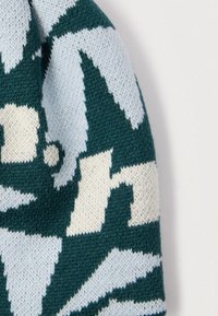 Pletená čiapka s geometrickým vzorom v zelenej, svetlomodrej a krémovej farbe. Mäkká textúra s guľatým tvarom a preloženým okrajom.