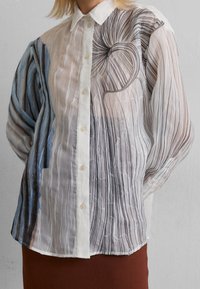 Genomskinlig skjorta med knappar som har en gradient av blå och svarta ränder, med abstrakta virvlande mönster och subtil vertikal plissé.