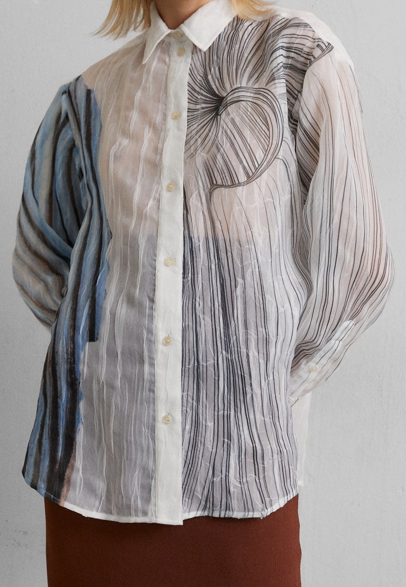 Genomskinlig skjorta med knappar som har en gradient av blå och svarta ränder, med abstrakta virvlande mönster och subtil vertikal plissé.