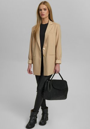 Beige stribet blazer med guldknap, sort tætsiddende top, sorte leggings og ankelstøvler. Sort håndtaske med struktureret design.