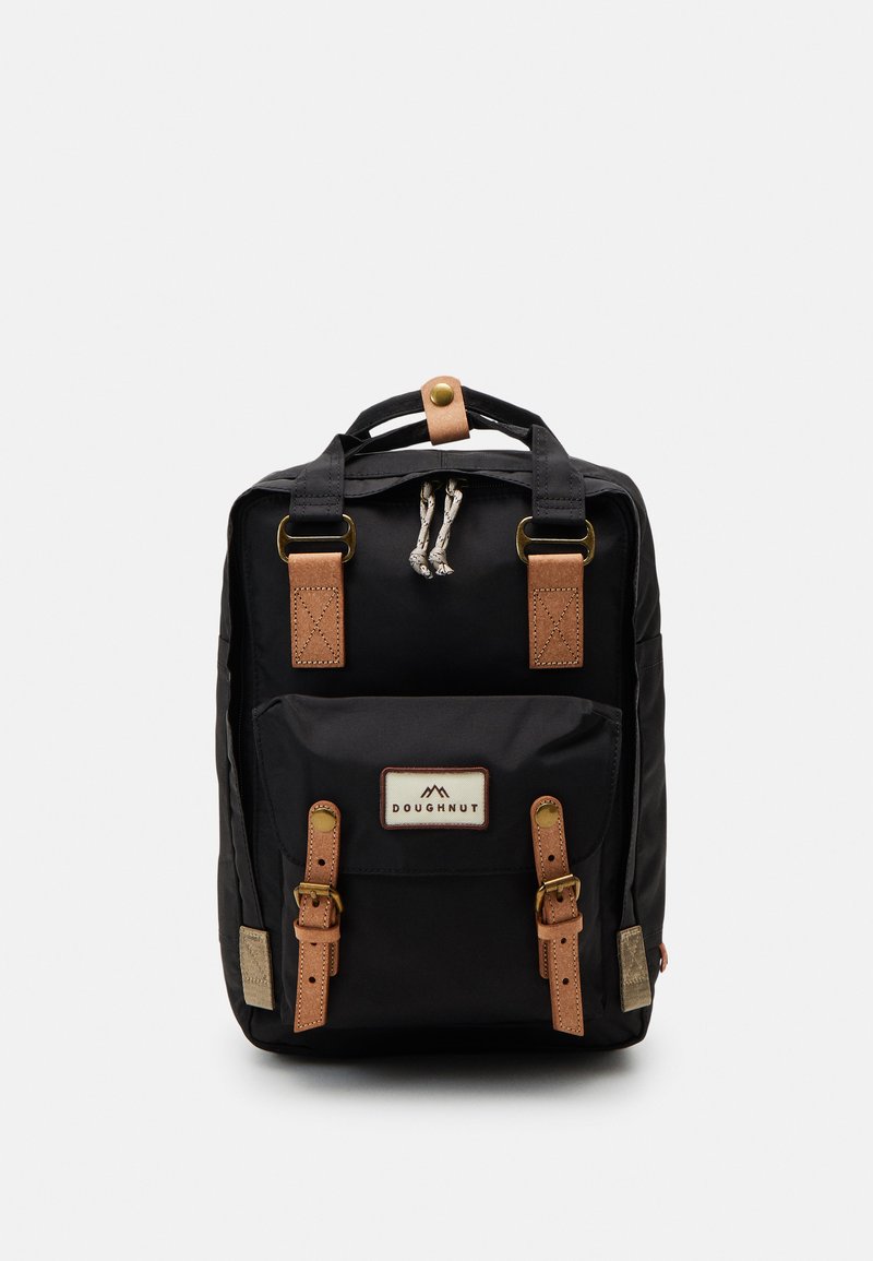 Black backpack with leather accents, featuring a top handle, adjustable straps, and a front pocket with a branded patch and decorative hardware.