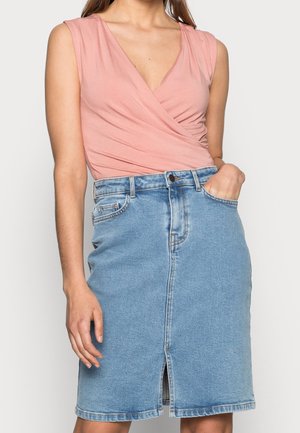 Jasnoróżowa kopertowa bluzka z krótkimi rękawami i głębokim dekoltem w serek, zestawiona z niebieską spódnicą dżinsową z rozporkiem z przodu i wzorem z pięcioma kieszeniami.