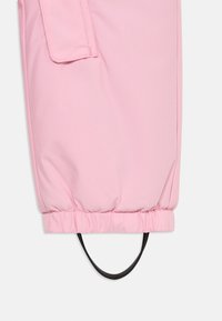 Manga de casaco acolchoado rosa com punho elástico, apresentando um laço de puxar preto e um bolso de aba na parte superior do braço. Textura de tecido suave.